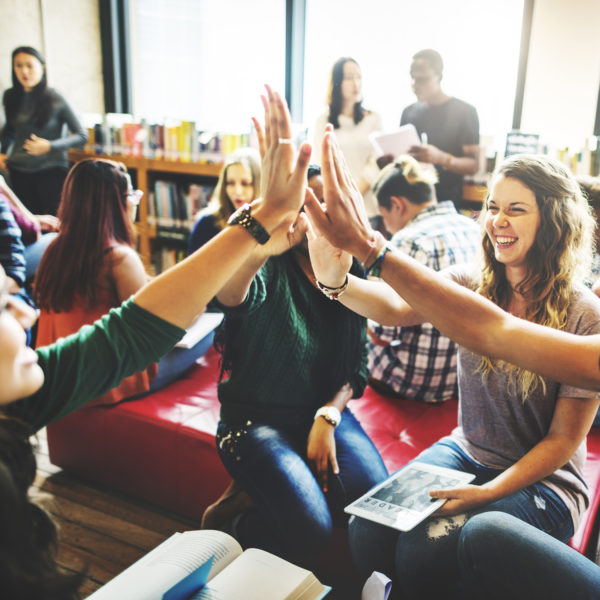 A group of young people in a meeting high-fiving each other