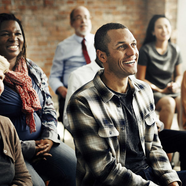 A diverse audience of adults smiling at a presenter out of shot