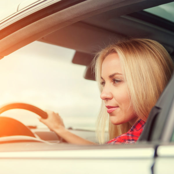 A women in the driver's seat of a car, looking out of the window