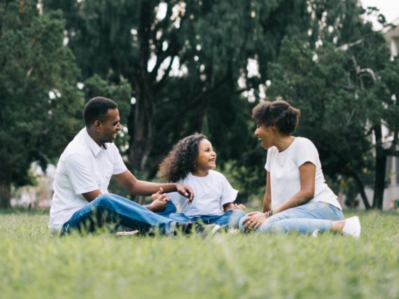 A smiling family sitting together on the grass