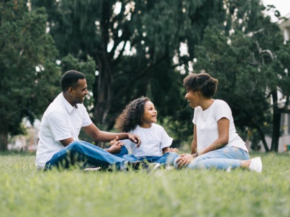 A smiling family sitting together on the grass