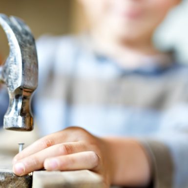 A child about to hammer a nail in to a piece of wood