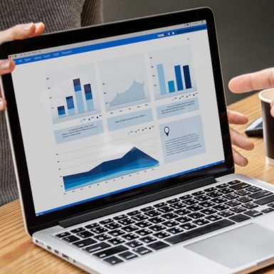 A hand pointing to data visualization on a laptop screen