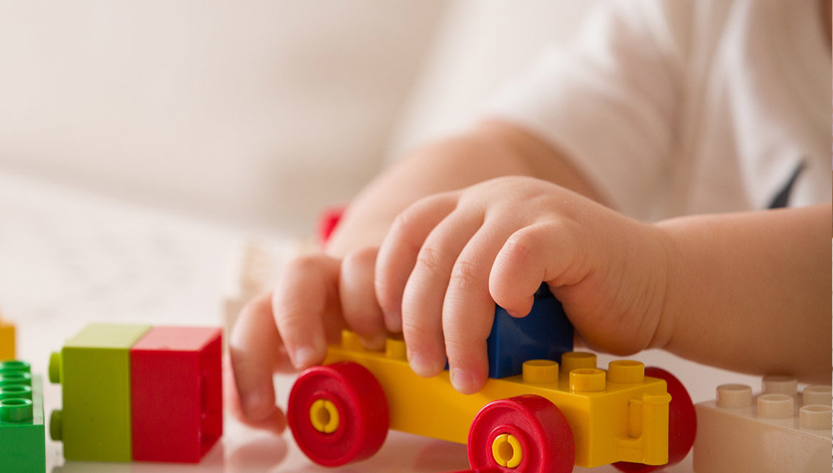 A close up of a child's hands, playing with building blocks