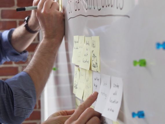 Two team members placing sticky notes on a board