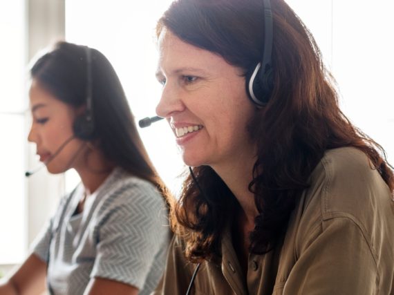 Two workers in call center, answering the phone