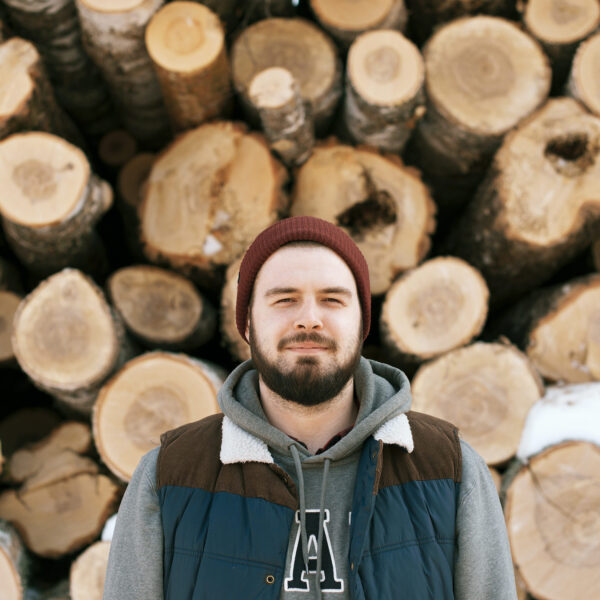 Man standing in front of cut trees